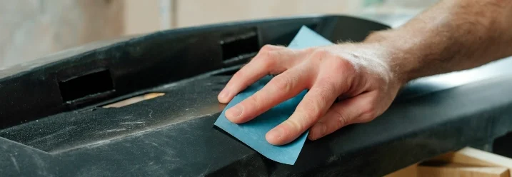 Person schleift eine Autostoßstange